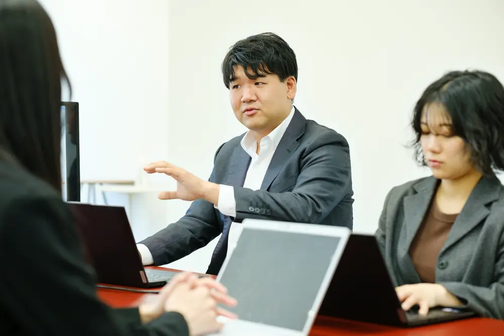 身振りを交えて話すスーツ姿の社員
