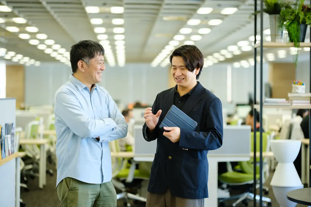 資料を手にオフィスで話す社員