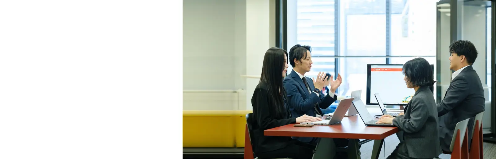 ノートパソコンを広げてテーブルを囲み話し合う社員