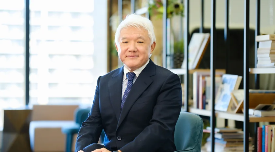 本棚の前に座る代表取締役 高橋巧