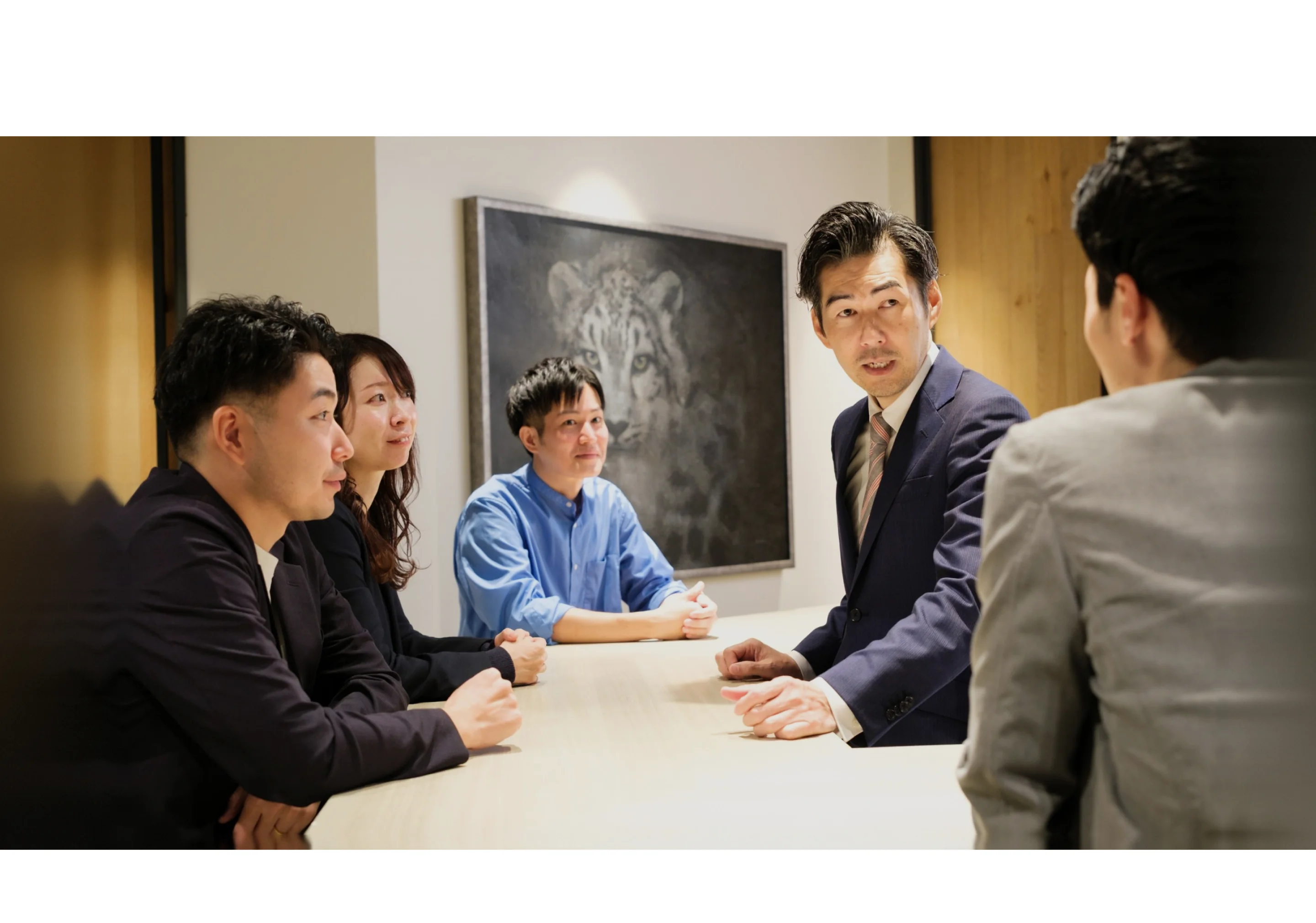 会議室のテーブルを囲んで話し合う社員たち