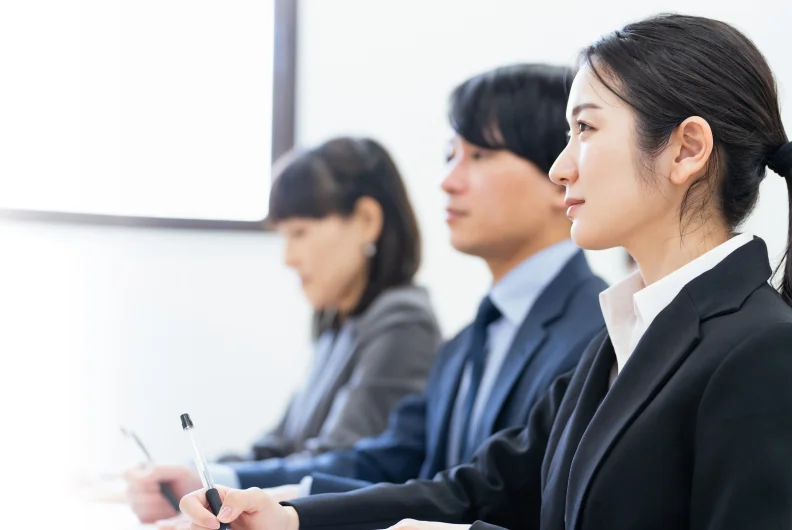 並んで座り話を聞くスーツ姿の社員たち