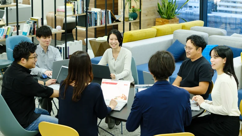 ソファ席でノートパソコンを囲んで話す社員たち