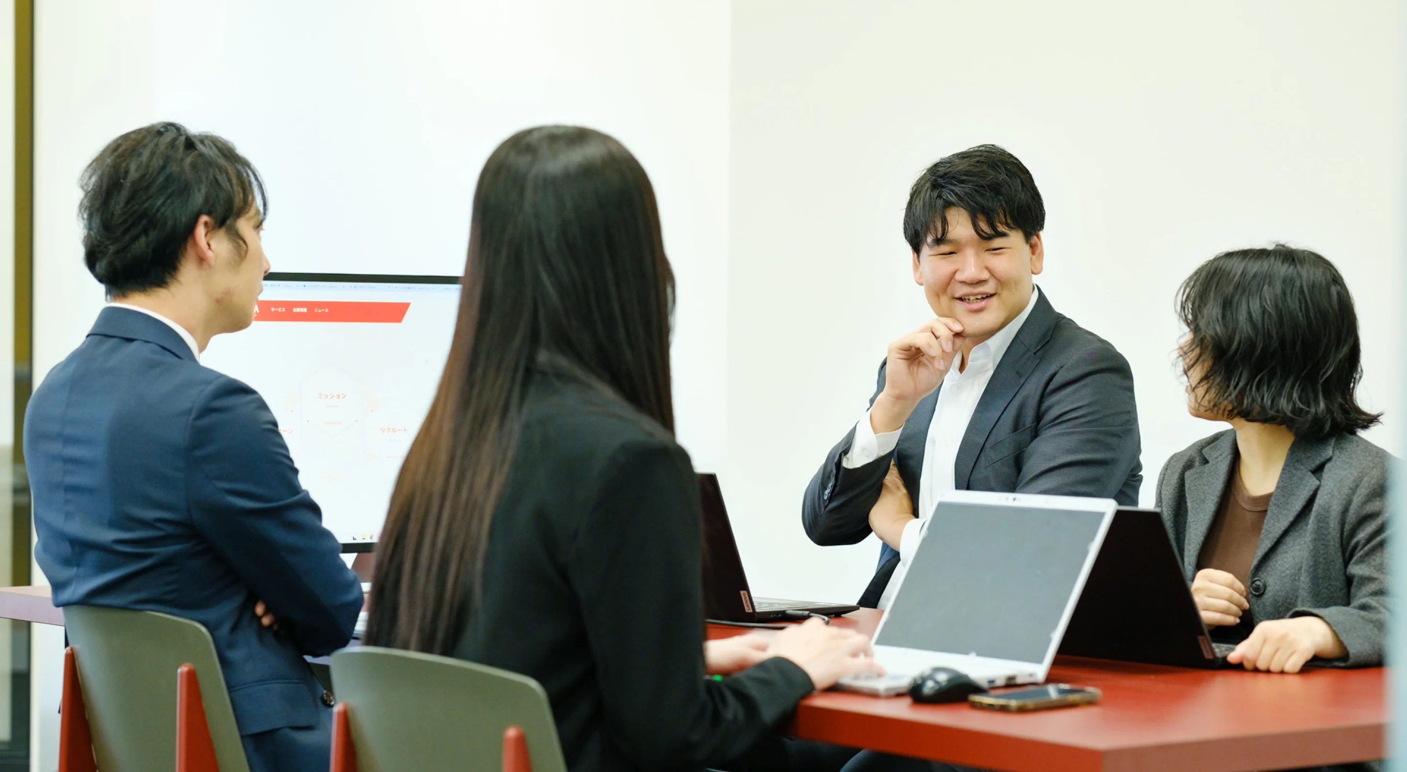 会議室でノートパソコンを前に話し合う社員たち