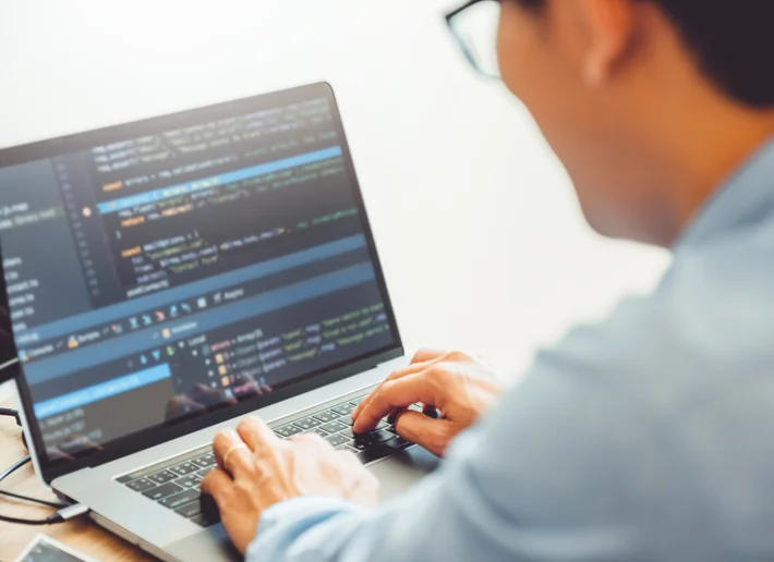 ノートパソコンでコードを書く社員