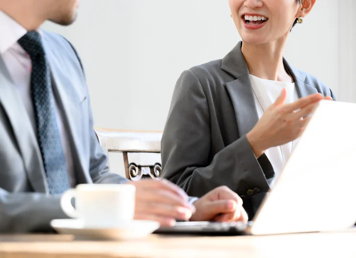 コーヒーを置いたテーブルで笑顔で話す社員