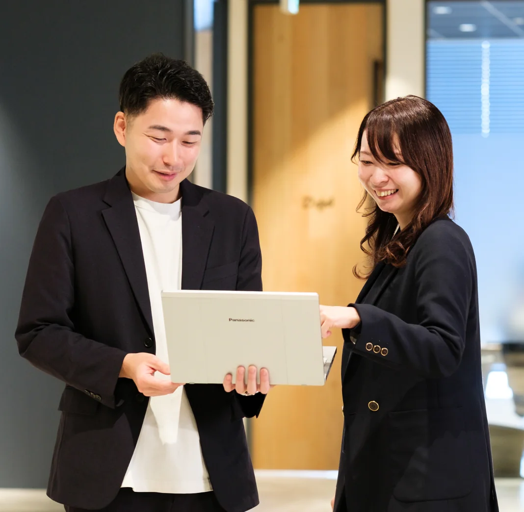ノートパソコンを手に話す男女の社員