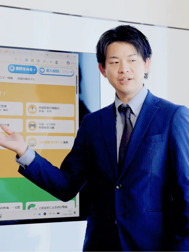 モニターの前でプレゼンするスーツ姿の男性