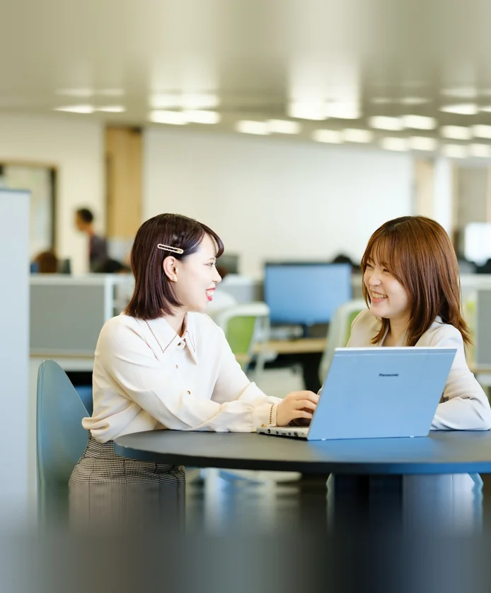 オフィスでノートパソコンを前に談笑する社員たち