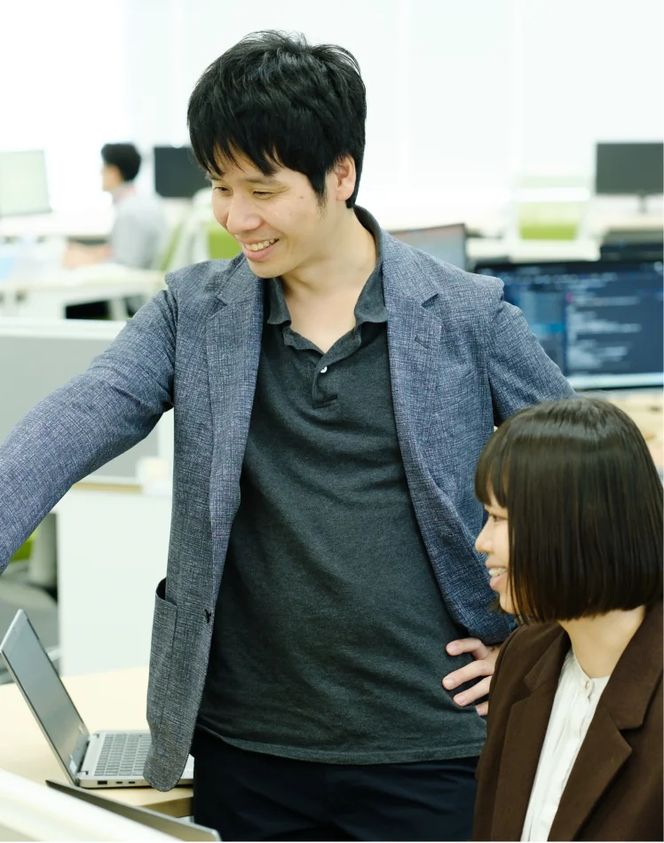 座っている社員に立って話しかける社員