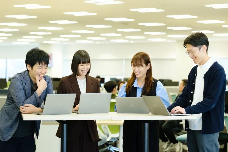 長机でノートパソコンを囲む4人の社員