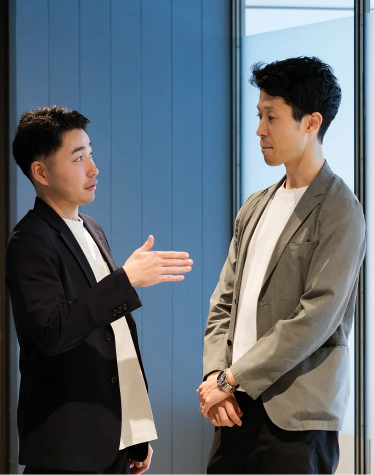 身振りを交えて話し合う二人の社員
