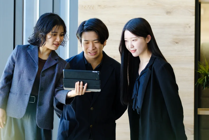 タブレットを囲んで画面をのぞき込む社員たち