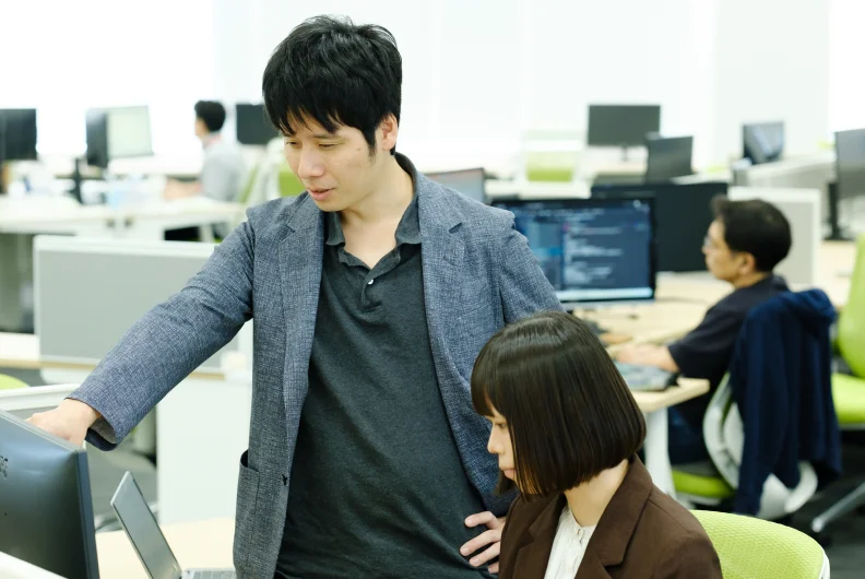 執務スペースで作業する社員に声をかける社員