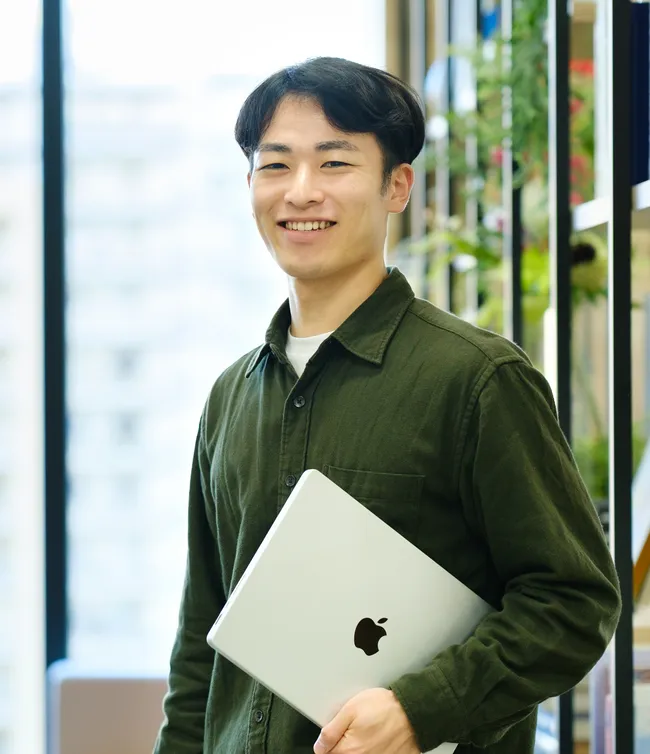ノートパソコンを手に笑顔を見せる社員