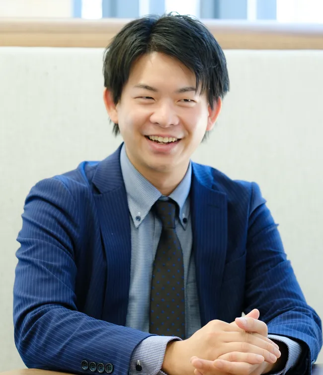 スーツ姿で笑顔を見せる社員
