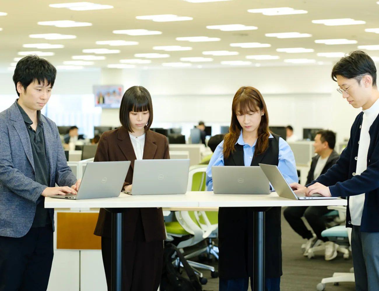 スタンディングテーブルに並んでノートパソコンを操作する社員