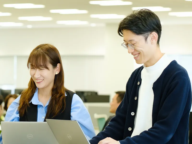 ノートパソコンを前に笑顔で話す社員