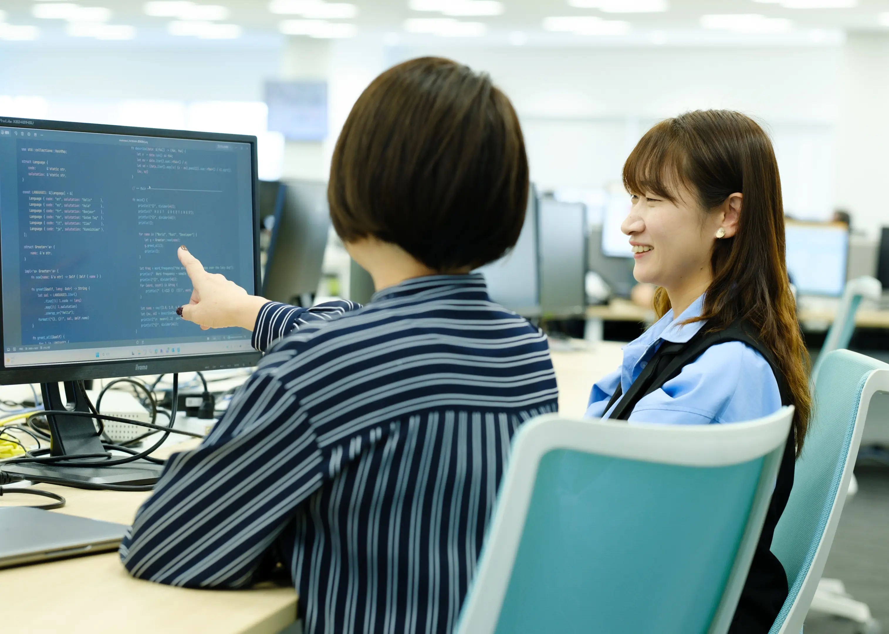モニターのコードを指差しながら話す2人の社員