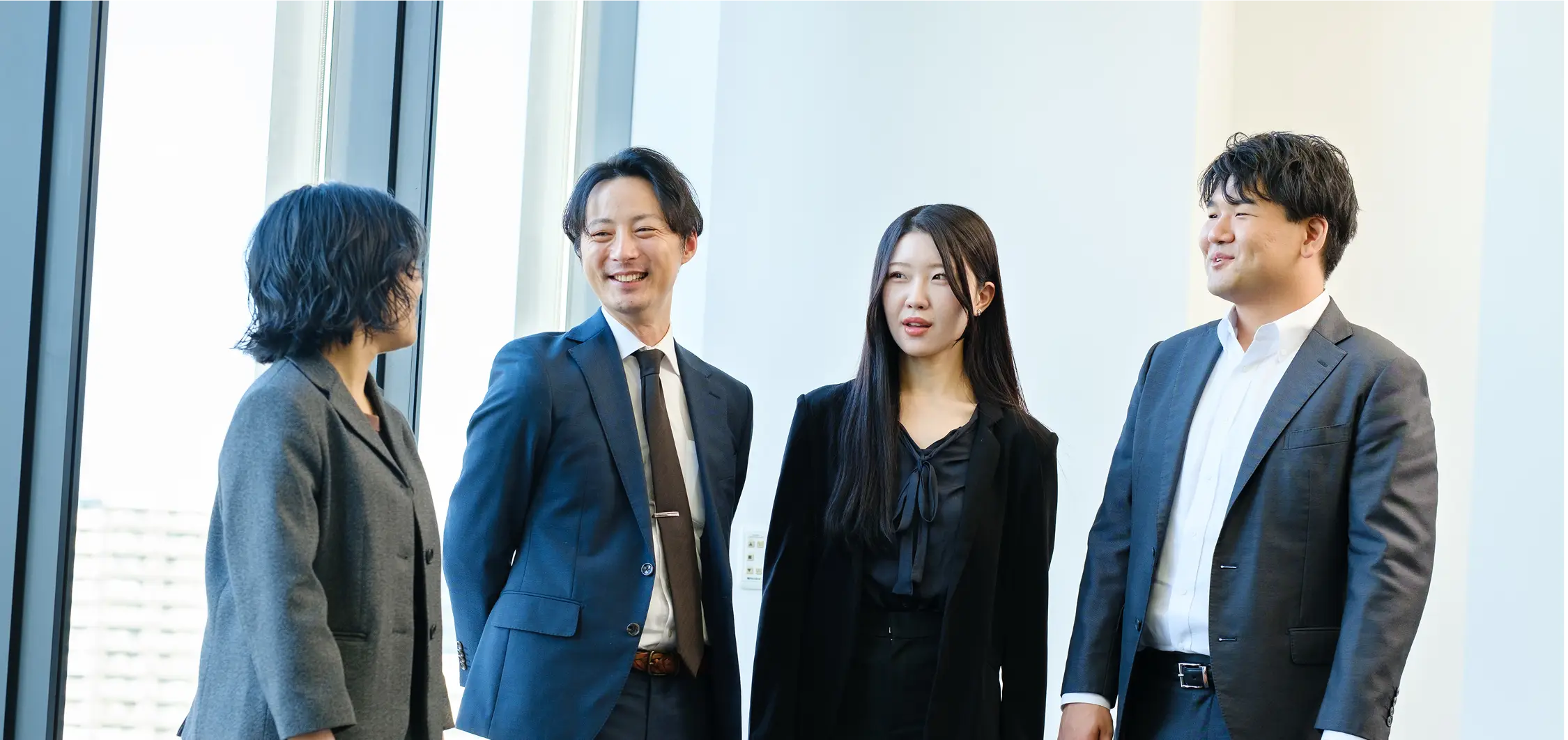 オフィスで立ち話をするスーツ姿の社員たち